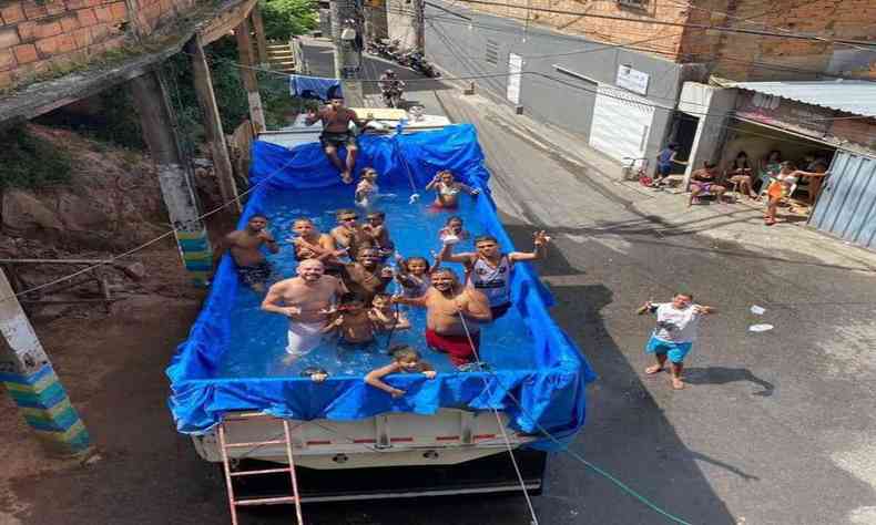 Algumas pessoas em cima de um caminho que virou uma piscina improvisada