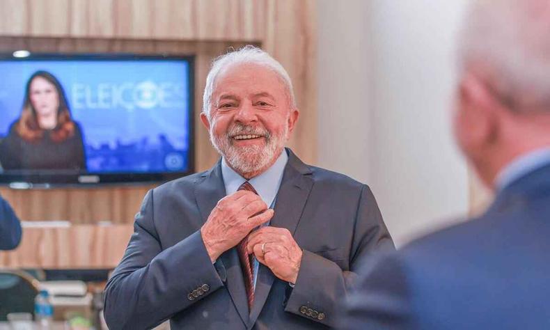Luiz Incio Lula da Silva (PT) sorri antes do debate da Globo; ele est de terno e ao fundo aparece uma tv com imagens do Jornal Nacional