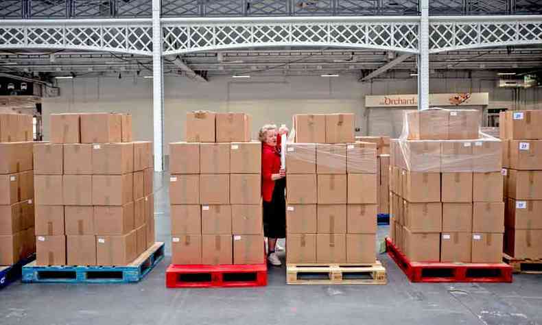 Voluntria trabalha em galpo de empacotamento de cestas de alimentos para populao carente de recursos, em Londres(foto: France Presse)