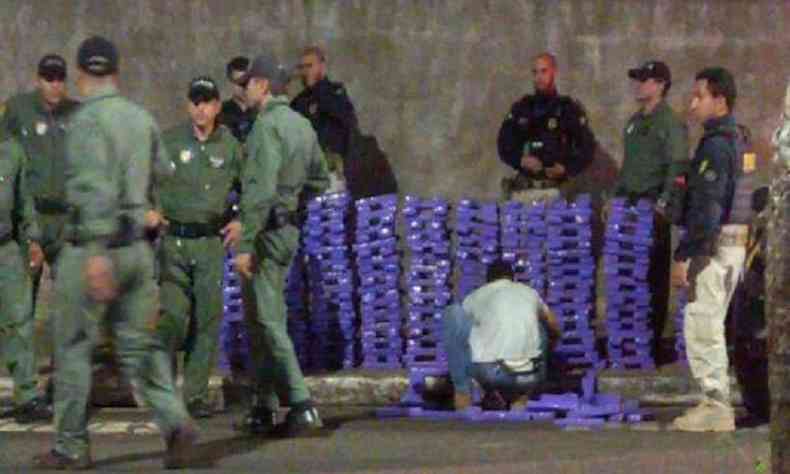 Policiais empilham os quase 550 tabletes de maconha embalados em papel roxo