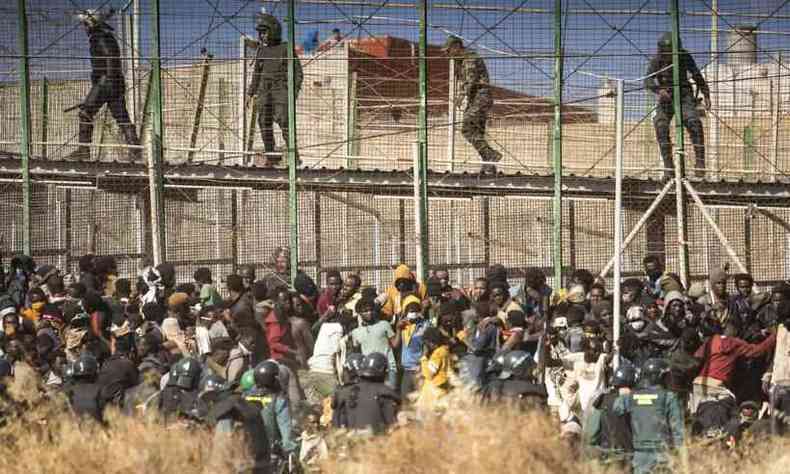 Observado por policiais marroquinos, grupo de migrantes é cercado por homens da Guarda Civil espanhola após pulares cerca que divide o Marrocos de Melilla, cidade espanhola no norte da África, em 24 de junho de 2022