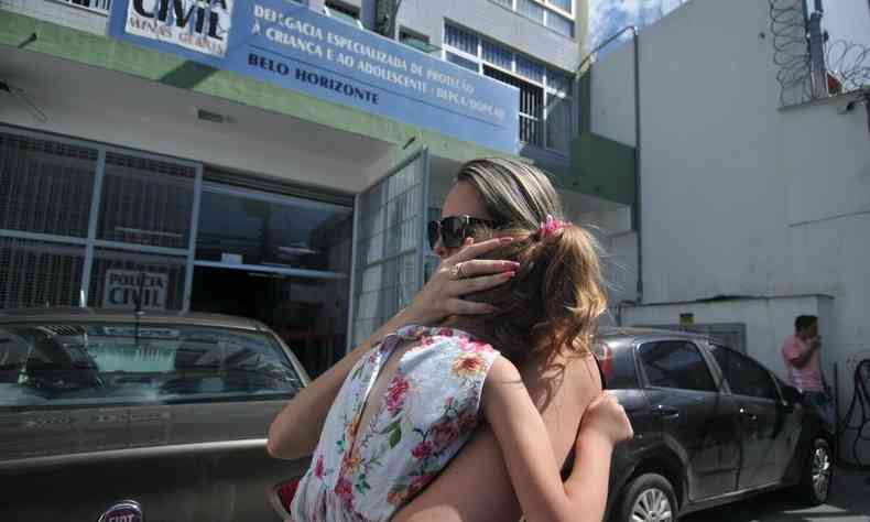 Karina segura sua filha no colo em frente a Delegacia Especializa de Proteo  Criana e ao Adolescente da Polcia Civil de Minas Gerais