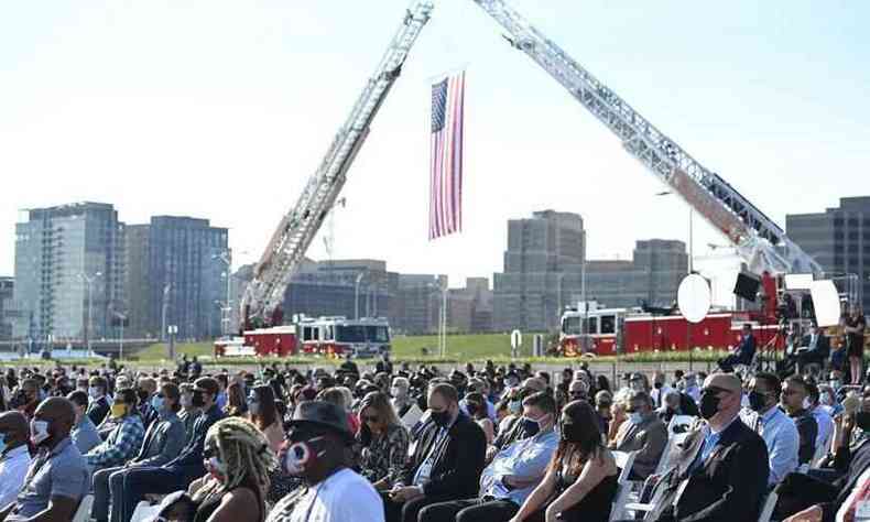 Bandeira americana hasteada por caminhões de bombeiros em cerimônia para homenagear os mortos no atentado de 11/9/2001