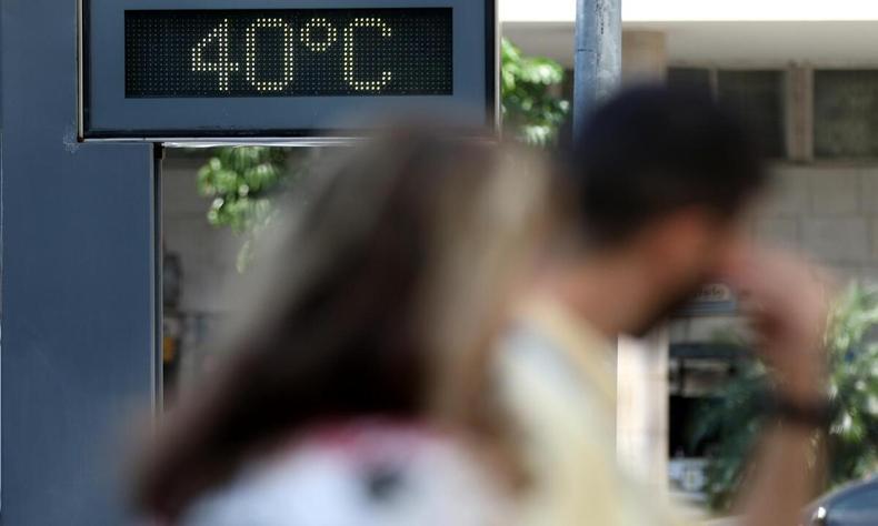 Calor continua em BH e Minas e deve permanecer até a próxima semana (foto: Tânia Rêgo/Agência Brasil) pessoas olhando o painel que marca os termômetros na casa dos 40°C