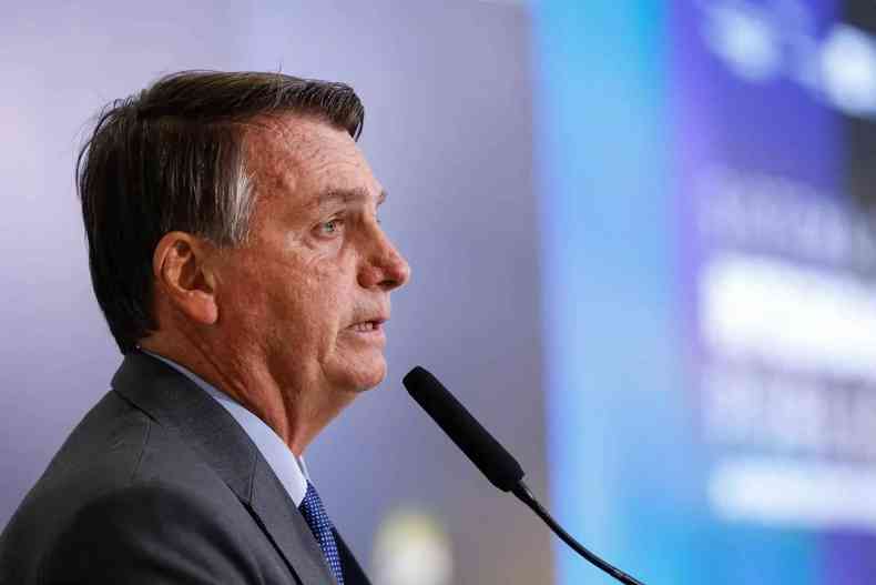Presidente Jair Bolsonaro de perfil falando em microfone