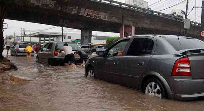 Motoristas empurram carros com a ajuda de pedestres em rea alagada pela chuva (foto: Joo Calazans/Esp DP/D.A Press)