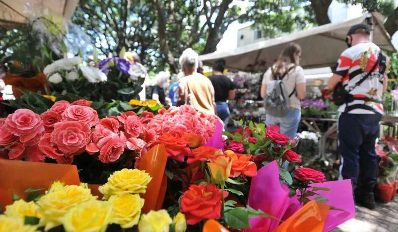 Flores em primeiro plano, transeuntes ao fundo.