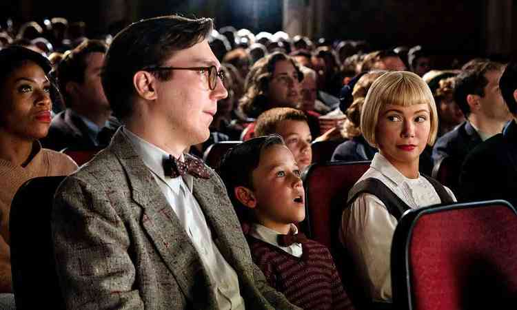 Cena de Os Fabelmans mostra o filho adolescente sentado no cinema ao lado dos pais e deslumbrado com as imagens na tela
