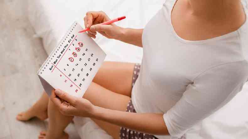 Mulher usando calendário para monitorar ciclo menstrual