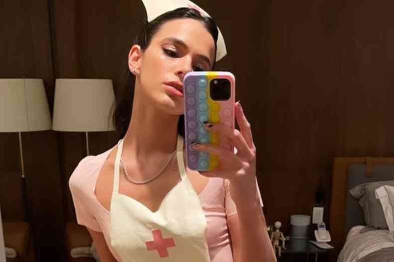 Bruna Marquezine tirando selfie com seu celular usando fantasia de 'enfermeira sexy' rosa com avental e chapu brancos