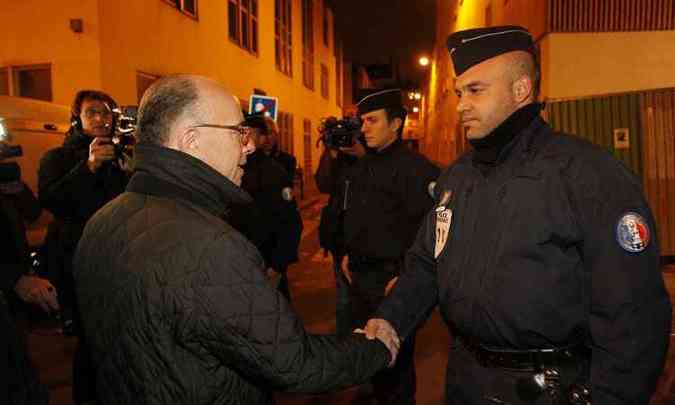 Ministro do Interior francs, Bernard Cazeneuve, cumprimenta policial em rua prxima ao local do atentado(foto: Matthieu Alexandre/AFP)