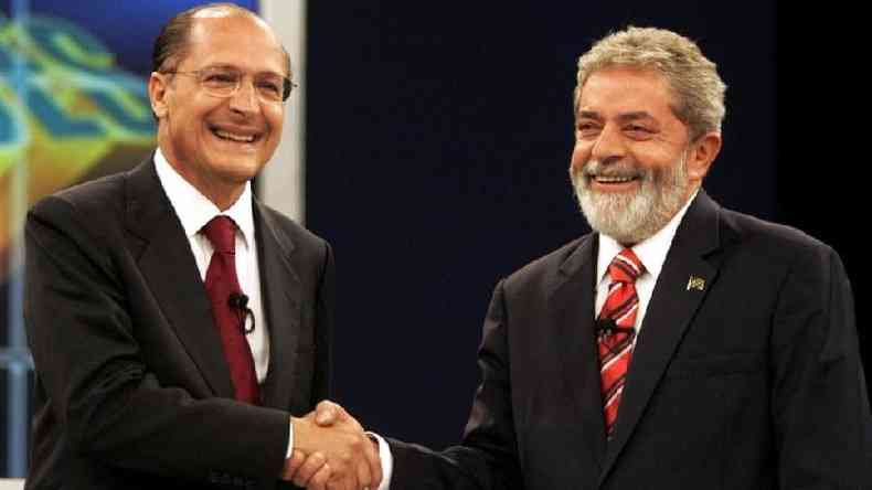 Alckmin e Lula sorriem enquanto apertam a mo
