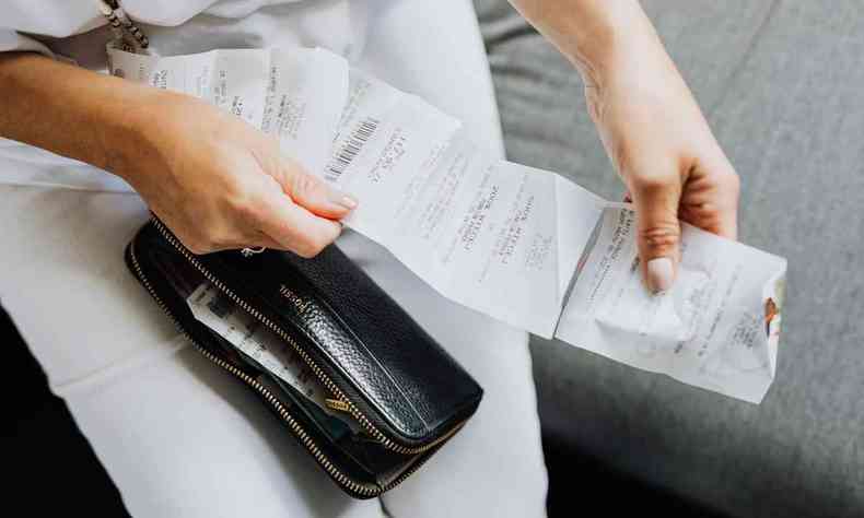 Mulher confere nota fiscal com carteira colo