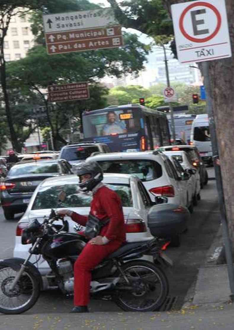 motociclista de roupa vermelha parado em ponto de txi