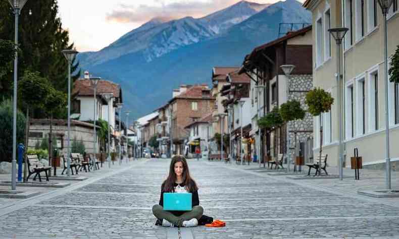Mulher sentada no meio da rua trabalhando no notebook