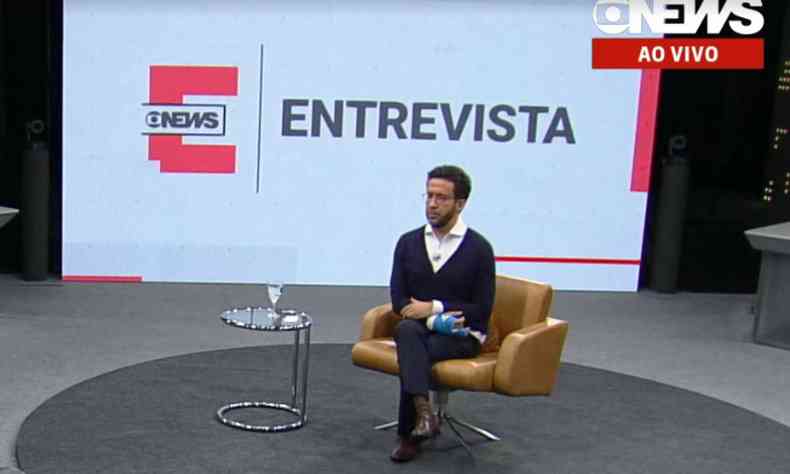 Andr Janones fala com a GloboNews; ao fundo a palavra 'Entrevista' escrita em fundo branco