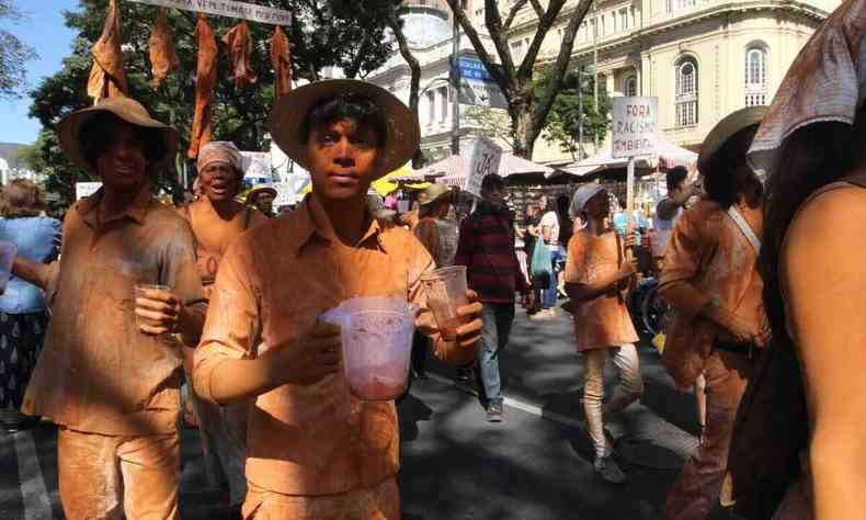 Ativista com o corpo coberto de lama oferece gua suja de barro em forma de protesto