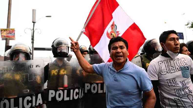 Homem com bandeira do Peru ao lado de foras policiais
