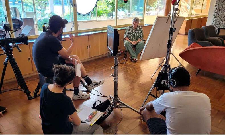 Professora Vera Casa Nova est sentada em cadeira rodeada por integrantes da equipe de filmagem do documentrio Uma carta para Mrio