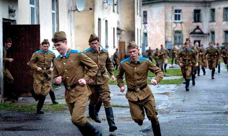 Atores vestidos como soldados correm na rua em cena de 'segredos de guerra'