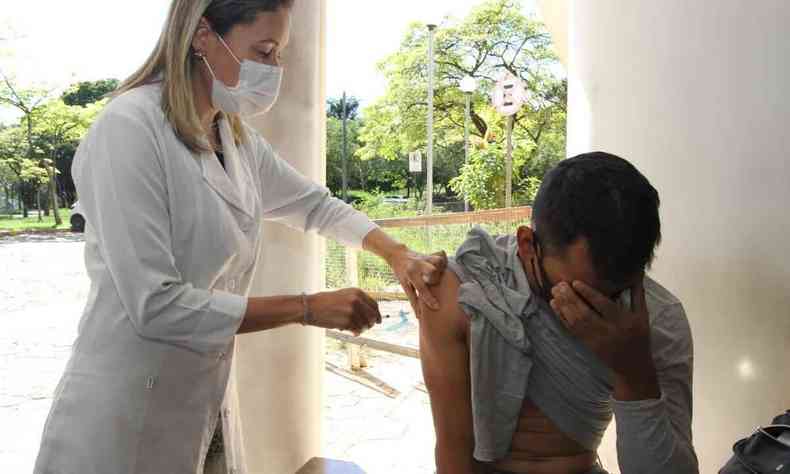 Cabea abaixada por ter pavor de agulha enquanto toma a vacina contra a COVID-19