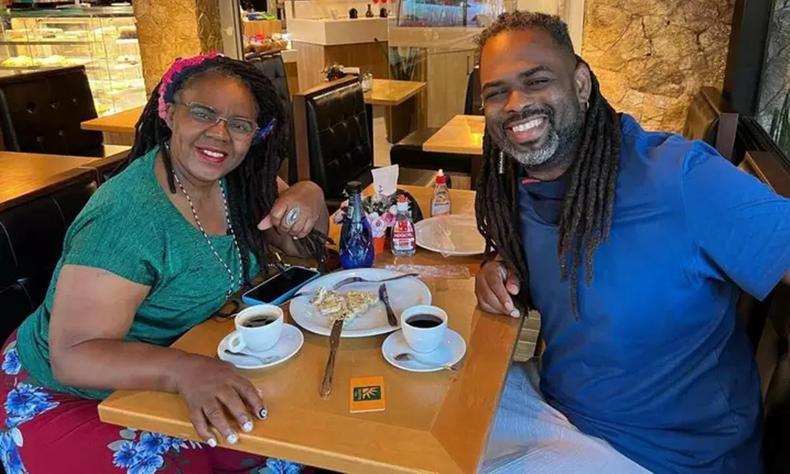 Foto de Manoel Soares e sua mae, dona Ivanete, sentados em uma mesa tomando caf. Eles sorriem olhando para a cmera