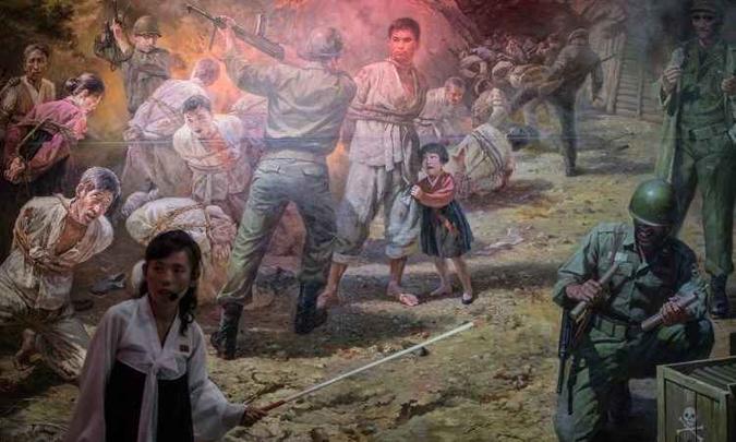 Guia mostra quadro que representa cena de soldados americanos se preparando para matar grupo de norte-coreanos(foto: Ed JONES / AFP) Guia mostra quadro que representa cena de soldados americanos se preparando para matar grupo de norte-coreanos(foto: Ed JONES / AFP)