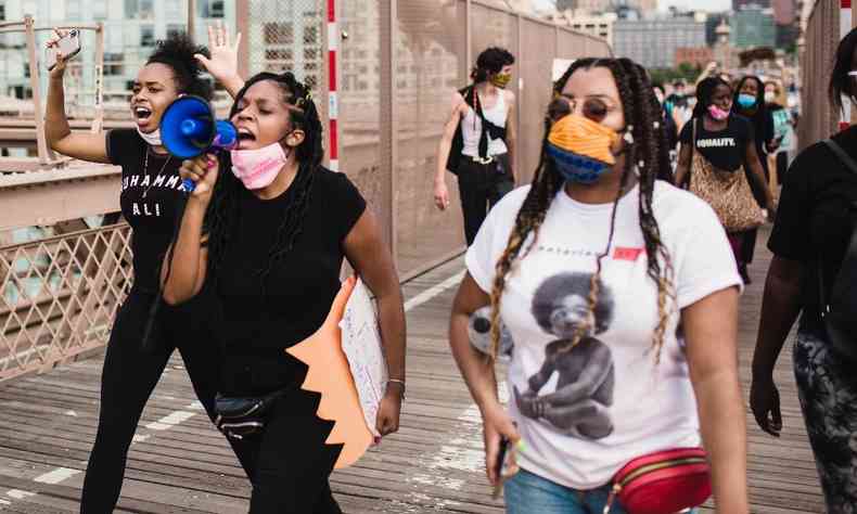 Mulheres negras em protesto com faixas e megafones