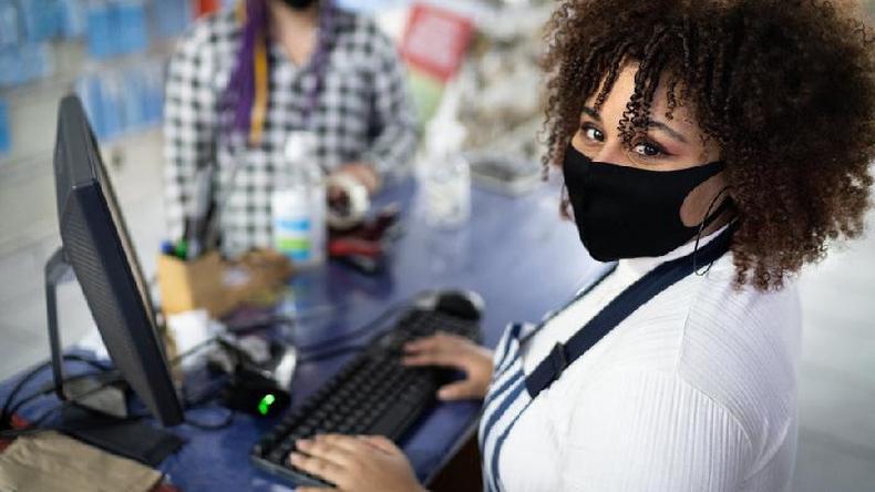 Doenças respiratórias afastam até 30% dos funcionários em alguns setores da economia(foto: Getty Images) Mulher usando máscara facial trabalhando como caixa em uma loja
