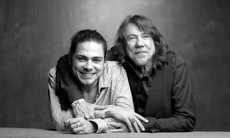 Os músicos Bruno Giorgi e Lenine sorriem para a câmera
