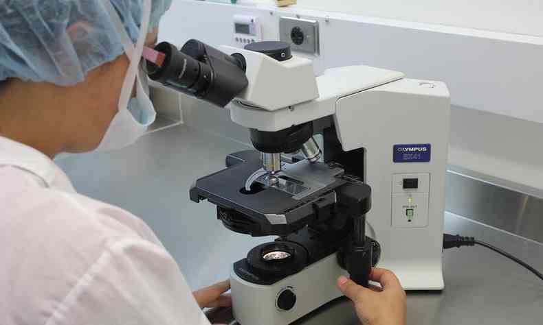 mulher olha em um microscpio dentro de um laboratrio