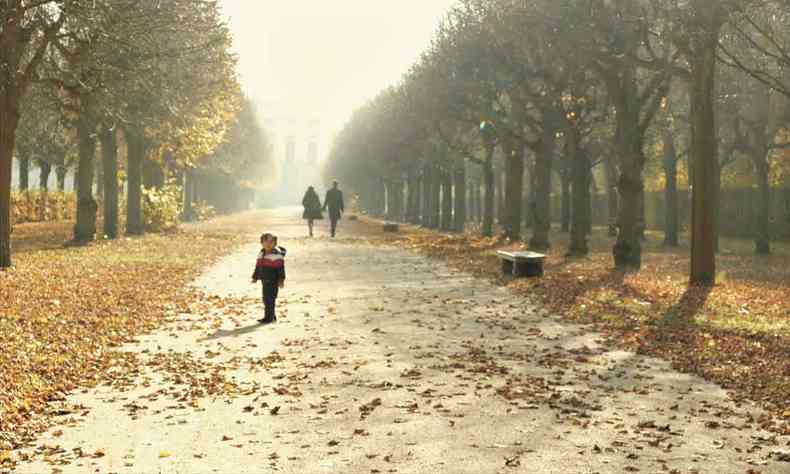 Criana caminha em ala de parque com folhas cadas 