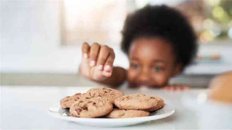 Menina negra pegando biscoito