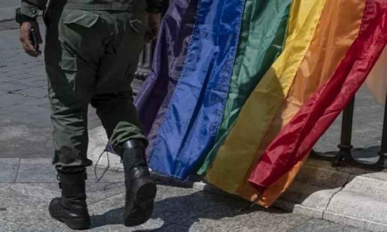 Militar passando ao lado de bandeira LGBT em manifestao da comunidade LGBT em Caracas, na Venezuela