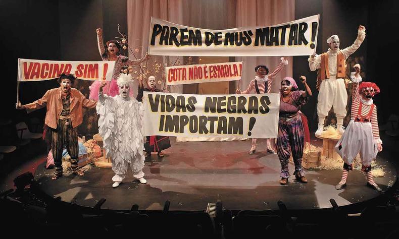 Peça 'A revolta dos perus' fala sobre a luta de classes(foto: Igor Cerqueira/divulgação) Atores erguem faixas onde estão escritas as palavras de ordem vacina sim, vidas negras importam e cota não é esmola, durante a peça A revolta dos perus