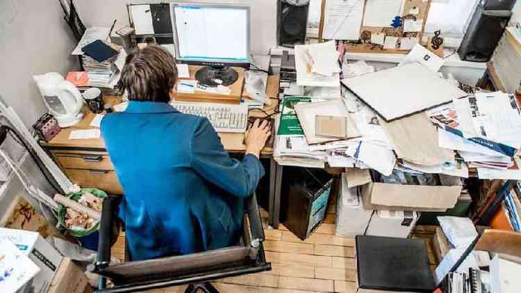 Pessoa sentada em mesa de escritrio completamente bagunada