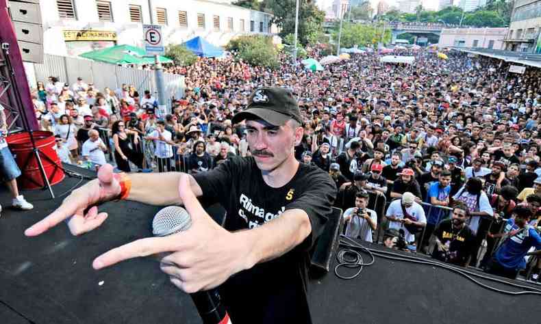 MC Miliano, vestindo preto, gesticula com ambas as mos na direo do pblico da final do Duelo de MCs na Rua Aaro Reis, em frente ao Viaduto Santa Tereza