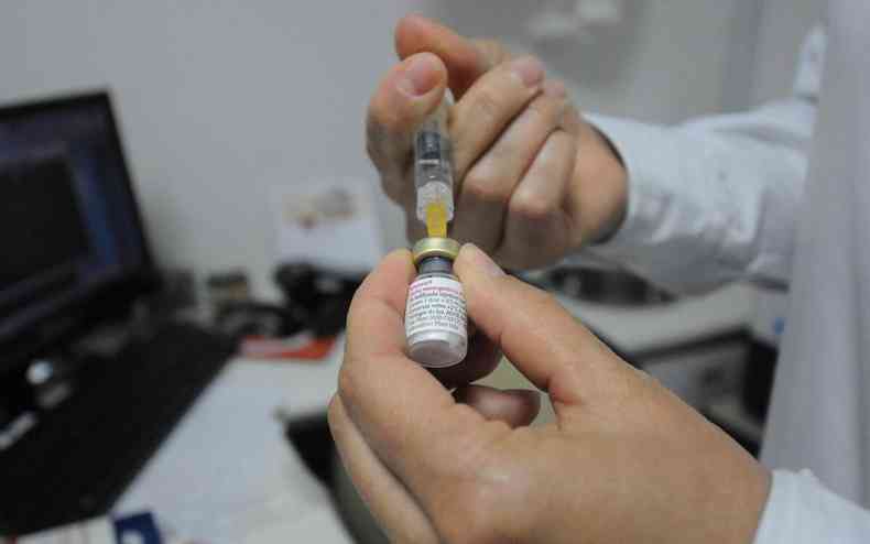 Uma mo preparando uma seringa para a vacina contra a meningite tipo C