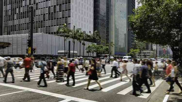 Dezenas de pedestres atravessando a Avenida Paulista