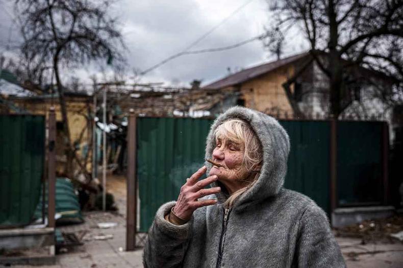 Idosa, de 76 anos, fuma cigarro em frente  casa dela, atingida por ataque areo na regio de Kiev, na Ucrnia