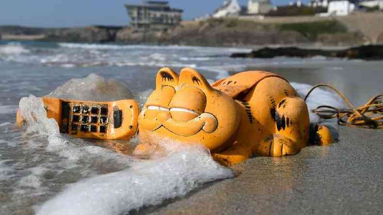 Telefone de personagem Garfield perto do mar na praia