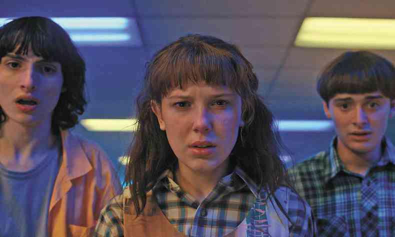 Os atores Finn Wolfhard (Mike Wheeler), Millie Bobby Brown (Eleven) e Noah Schnapp (Will Byers), de p, fazem expresso de surpresa em cena de stranger things 