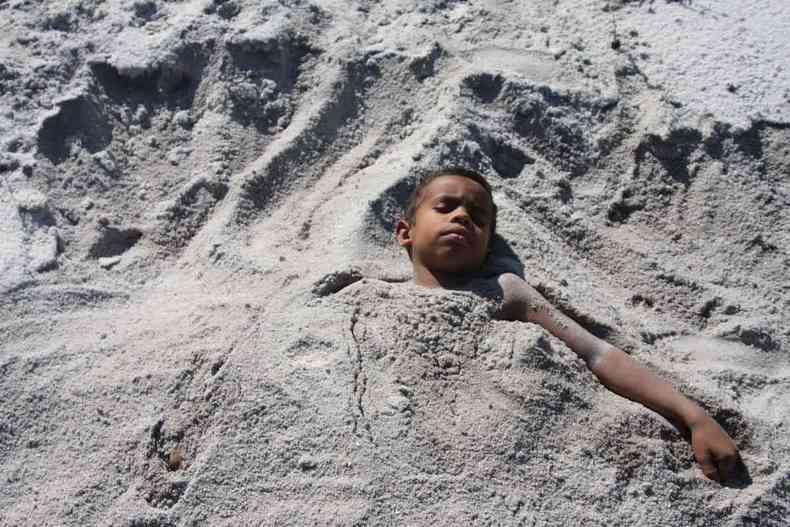 Criança enterrada na areia, com cabeça e braços de fora, em cena do filme Sopro