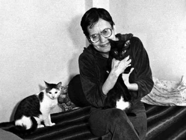 Poeta Orides Fontela segura gato e  observada por outro gato