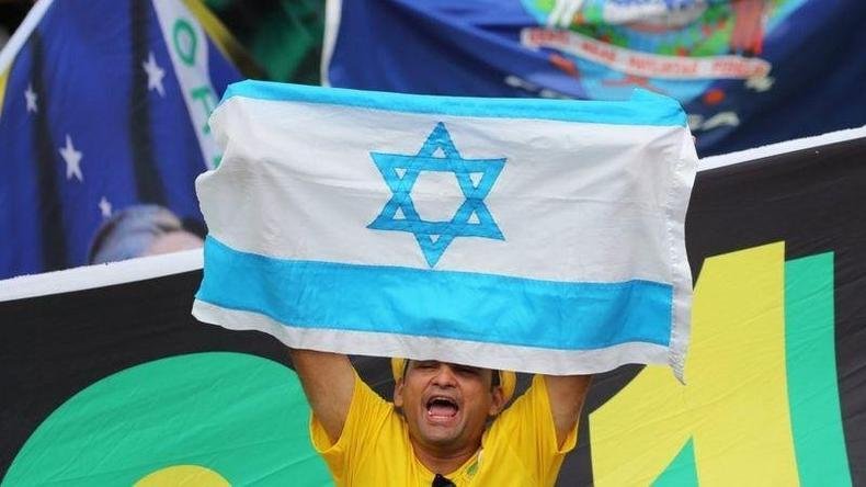 Uso de símbolos como a estrela de David ou a bandeira de Israel em eventos evangélicos no Brasil se tornou comum nos últimos anos, especialmente entre grupos religiosos ligados ao bolsonarismo(foto: Reuters) Homem segura bandeira de Israel