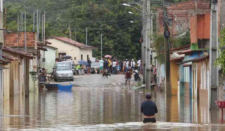 Casas inundadas pela chuva. Pessoas reunidas no fundo da imagem