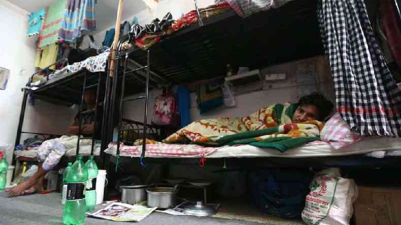 Um trabalhador de Bangladesh descansa na cama em um campo de trabalho privado no Catar