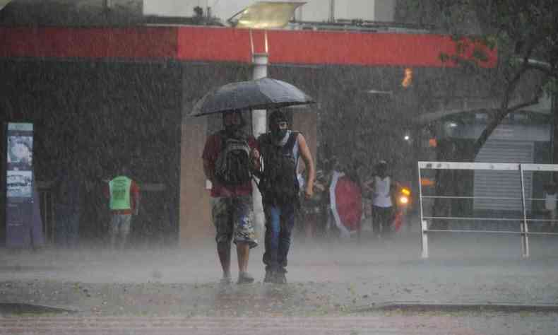 dois homens se protegem de chuva debaixo de guarda-chuva