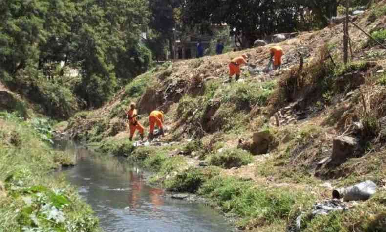 Funcionrios capinando margem de rio