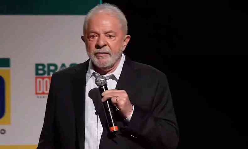 Lula, de palet preto e blusa branca, falando ao microfone